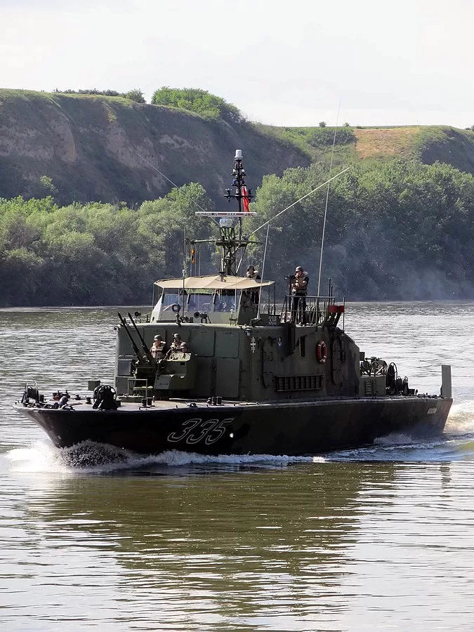 A vigilant border guard stands watch over the Danube, marking the line between established order and untamed possibility.